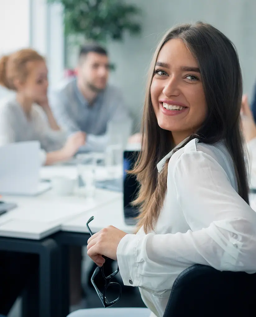 Eine junge Maklerin lächelt in die Kamera während eines Meetings