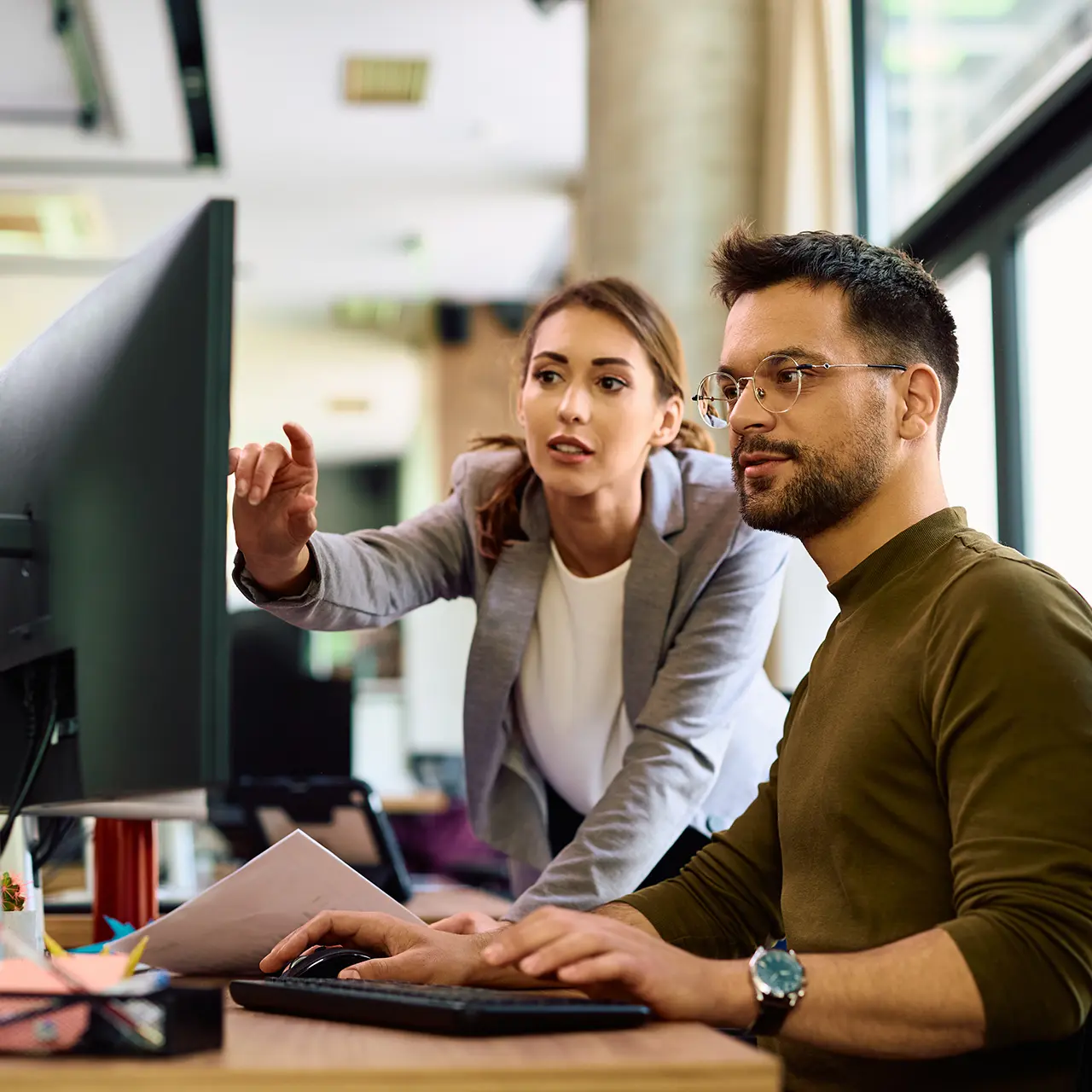 Jungmakler Zwei Jungmakler arbeiten gemeinsam vor einem Computerbildschirm