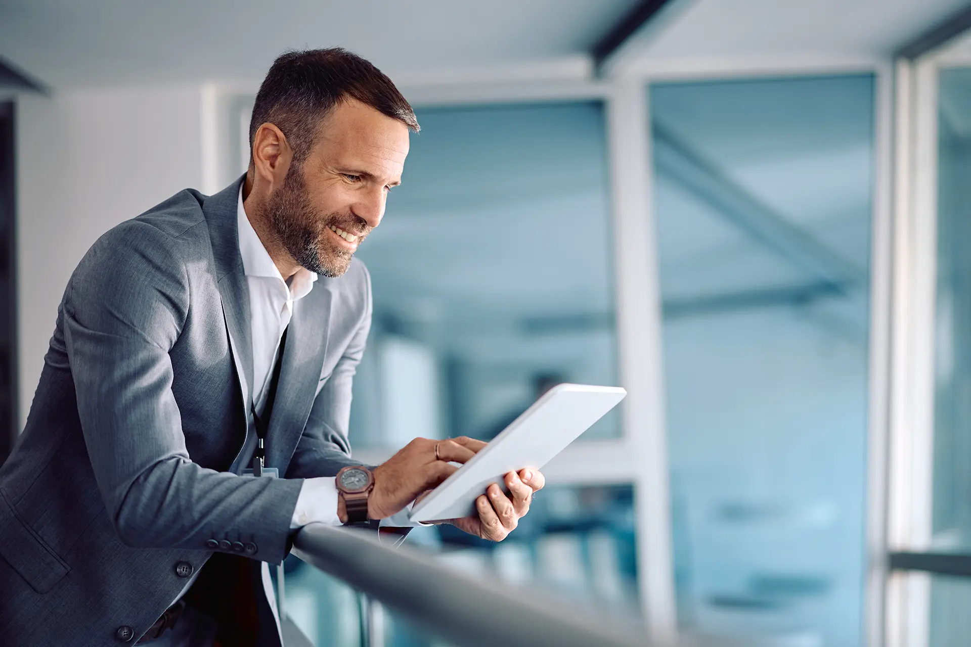 Ein zufriedener Makler betrachtet das Display seines Tablets 