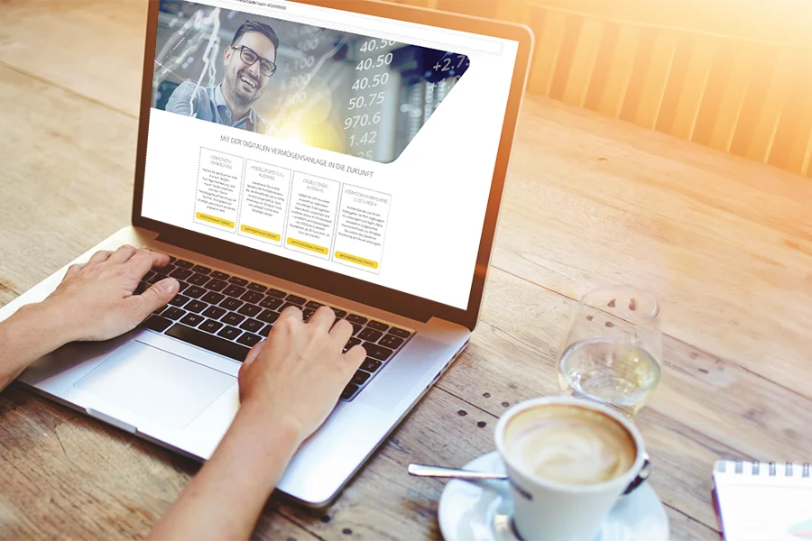 Person am Laptop mit Website und Kaffee Person tippt auf Laptop mit Website auf dem Bildschirm. Ein Kaffee steht daneben.