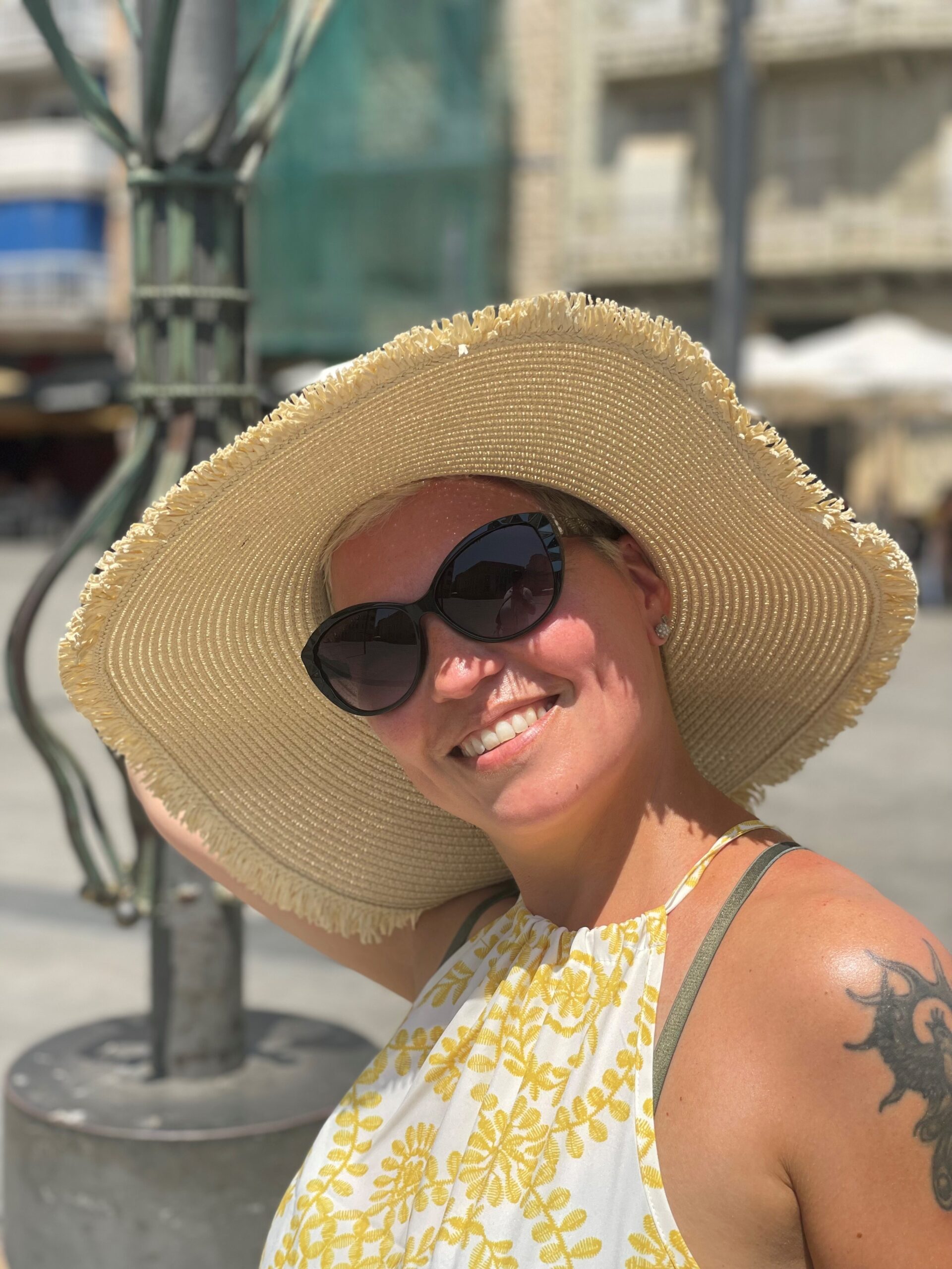 Eine Frau trägt einen großen Strohhut und eine Sonnenbrille.