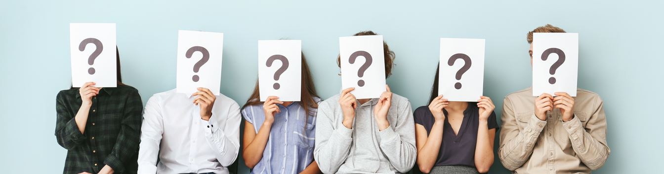 Gruppe von Personen hält Fragezeichenkarten vor ihre Gesichter. Die Identität der Personen ist verborgen.