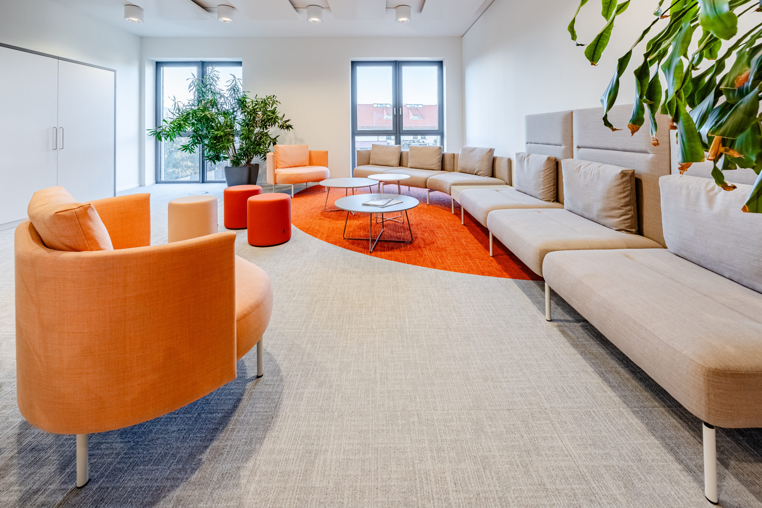 Ein hell erleuchteter Raum mit bequemen Sofas und Sesseln. Die Einrichtung ist modern und einladend.