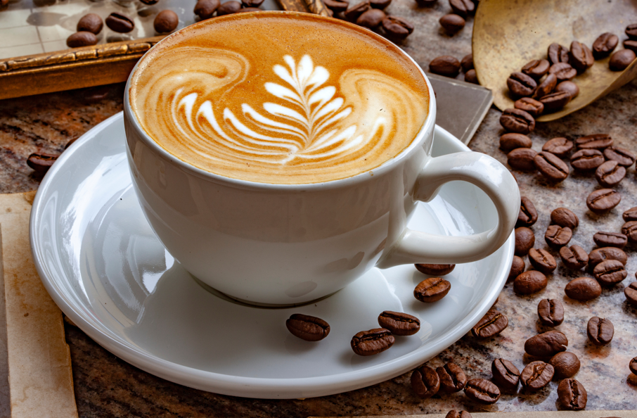 Ein Kaffee in einer weißen Tasse auf einem Teller. Der Kaffee hat ein schönes Milchschaum-Muster.