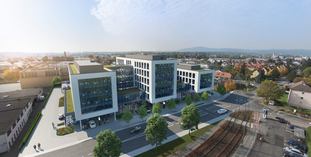 Ein großes, modernes Bürogebäude mit mehreren Stockwerken und einer großen Glasfassade. Das Gebäude ist von Bäumen und Grünflächen umgeben.