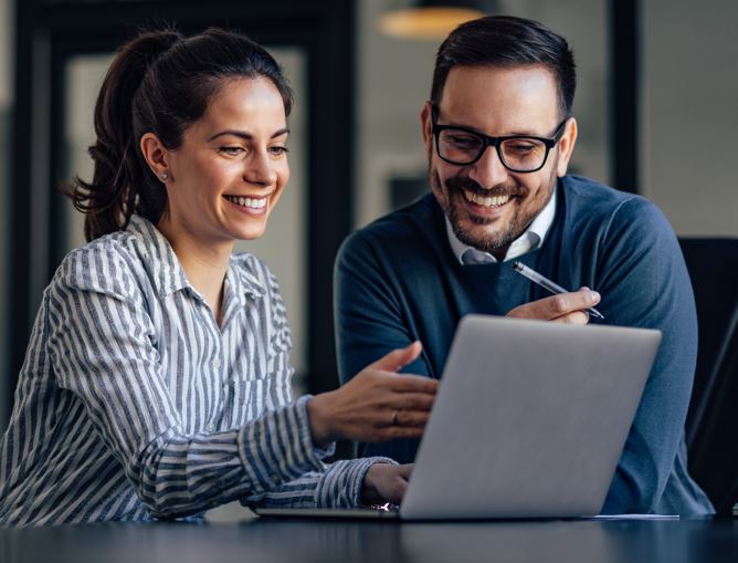Ein Mann und eine Frau betrachten gemeinsam einen Laptop. Sie arbeiten zusammen.