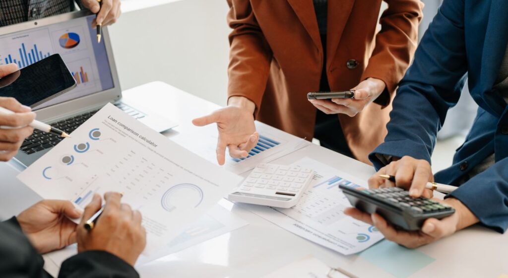 Ein Team bespricht Finanzberichte und verwendet einen Taschenrechner.