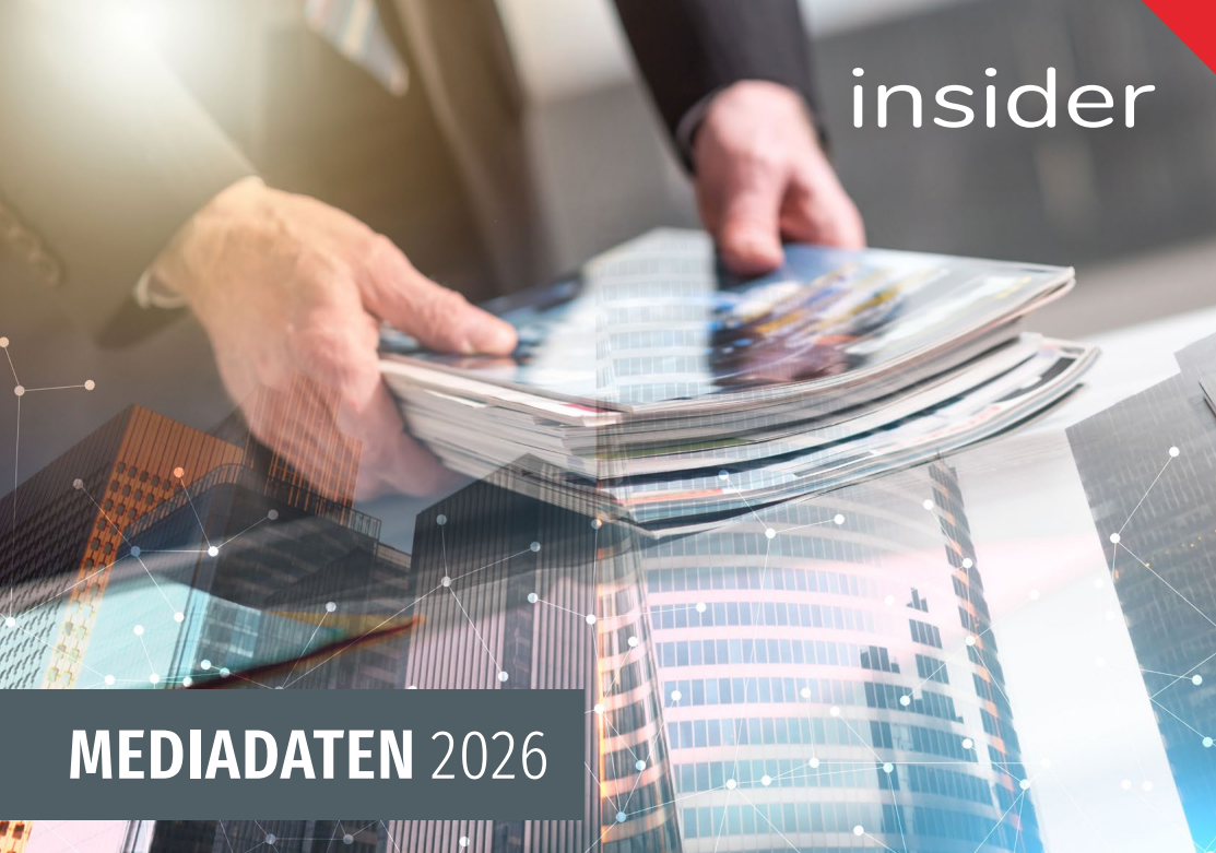 Ein Mann in einem schwarzen Anzug hält eine Mappe Zeitungen. Der Hintergrund zeigt ein modernes Gebäude.