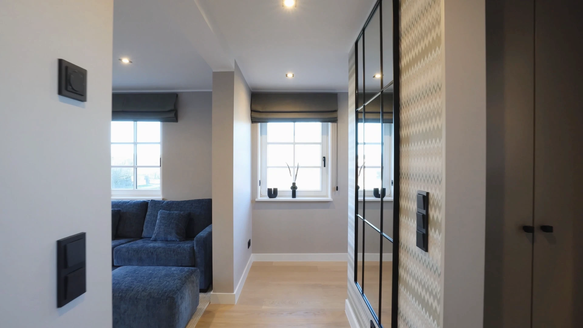 Ein heller Raum mit blauen Sofas und großen Fenstern. Blick in einen modernen Wohnbereich.