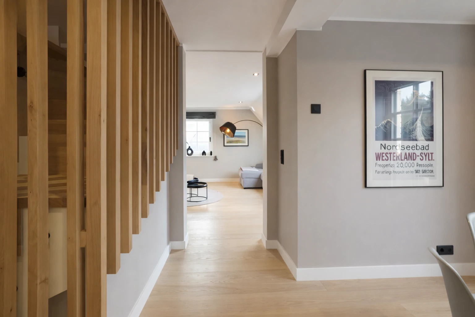 Ein heller, offener Raum mit Holzverkleidung und einem Poster an der Wand, im Hintergrund ein weiterer Raum.