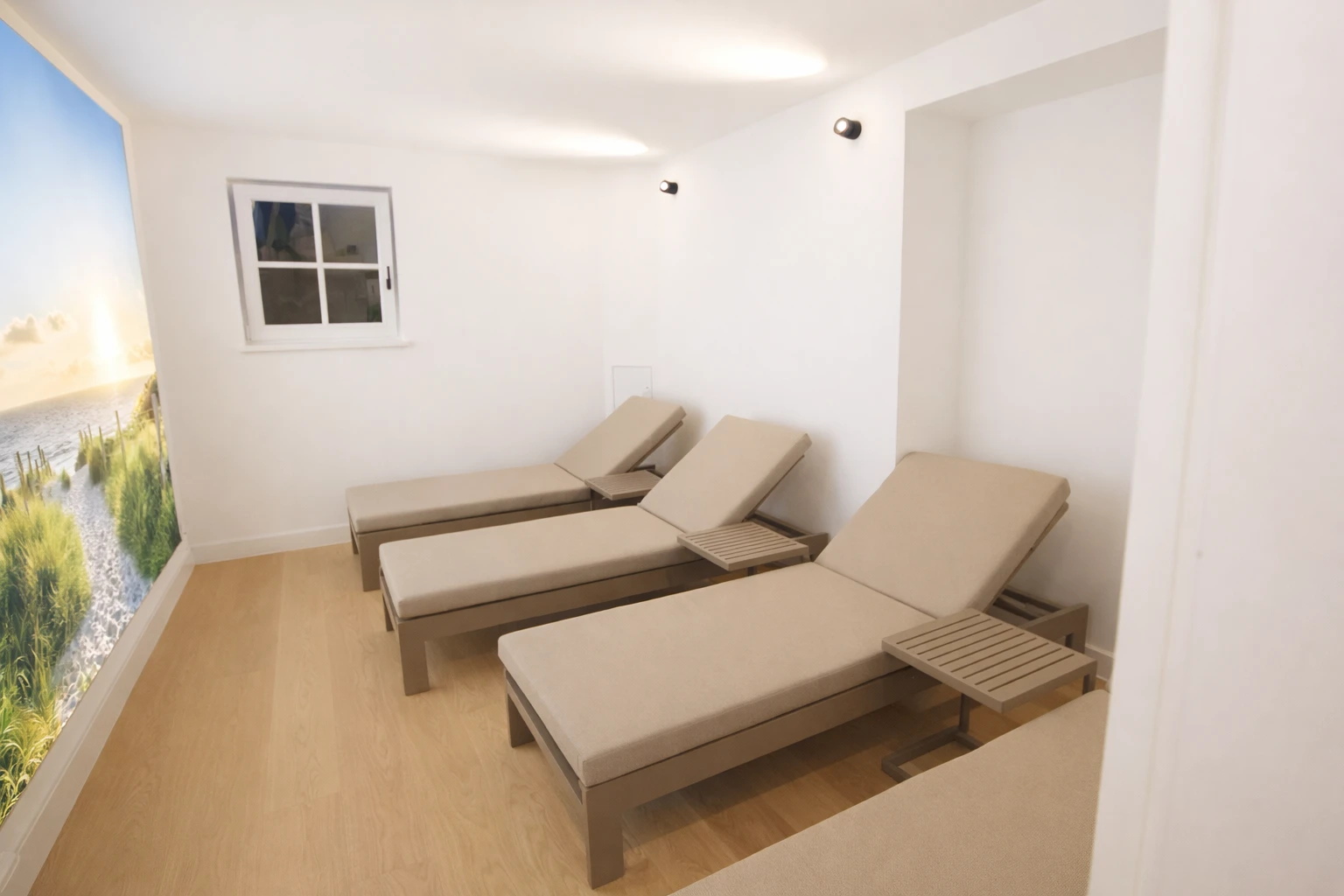 Ein Raum mit drei beige Liegestühlen und einem Fenster.