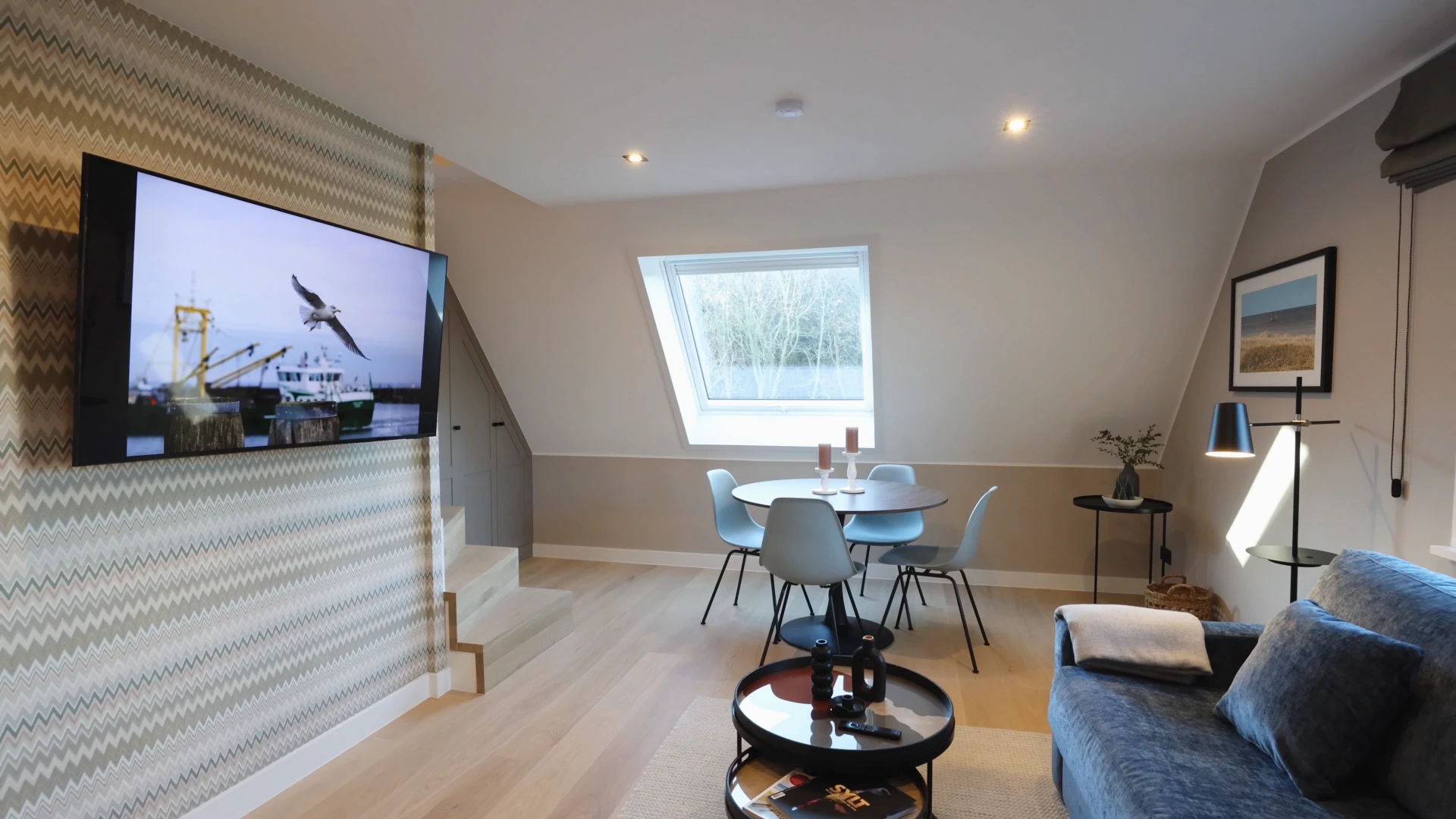 Ein modernes Wohnzimmer mit einem großen Fernseher, einem Essbereich und einem Sofa. Der Raum ist hell und freundlich.