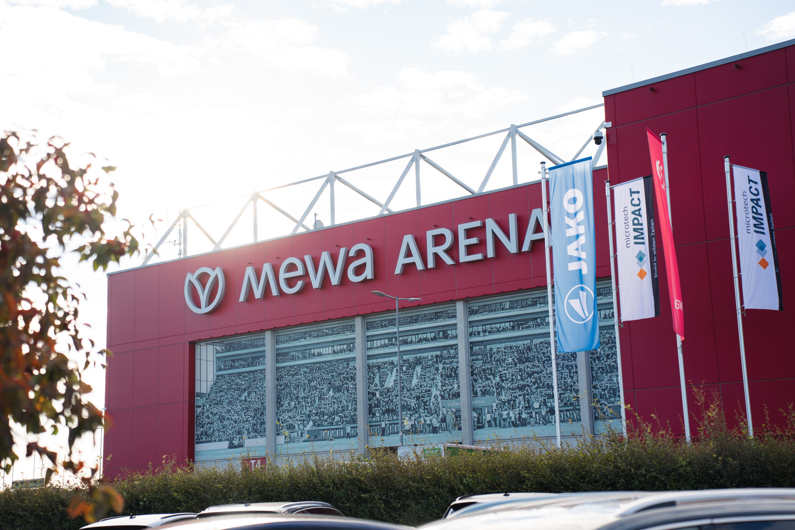 Ein großes, rotes Gebäude mit der Aufschrift Mewa Arena. Es sieht aus wie ein Fußballstadion.