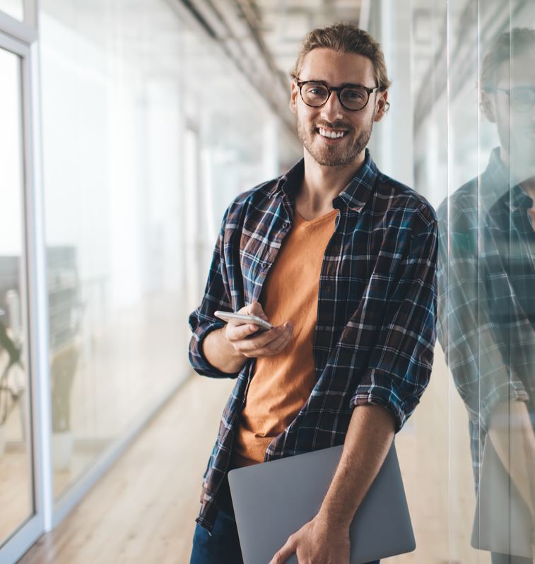 Ein lächelnder junger Mann mit Laptop und Smartphone
