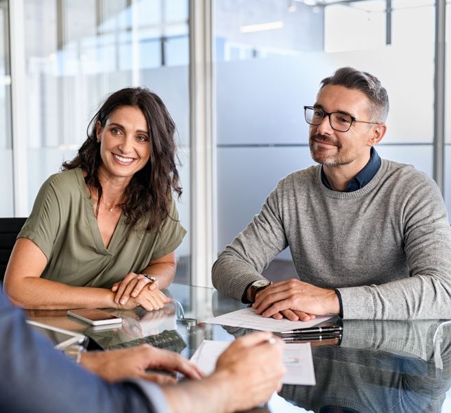 Ein Mann und eine Frau sitzen an einem Tisch. Sie lächeln und unterhalten sich.