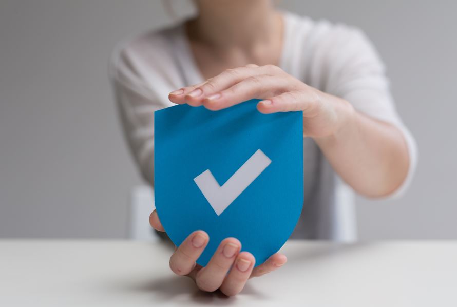 Eine Frau hält ein blaues Schild mit einem weißen Haken.