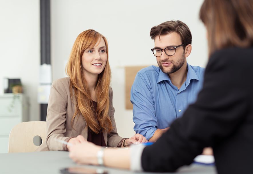 Ein Paar mittleren Alters sitzt an einem Tisch und spricht mit einer Frau.