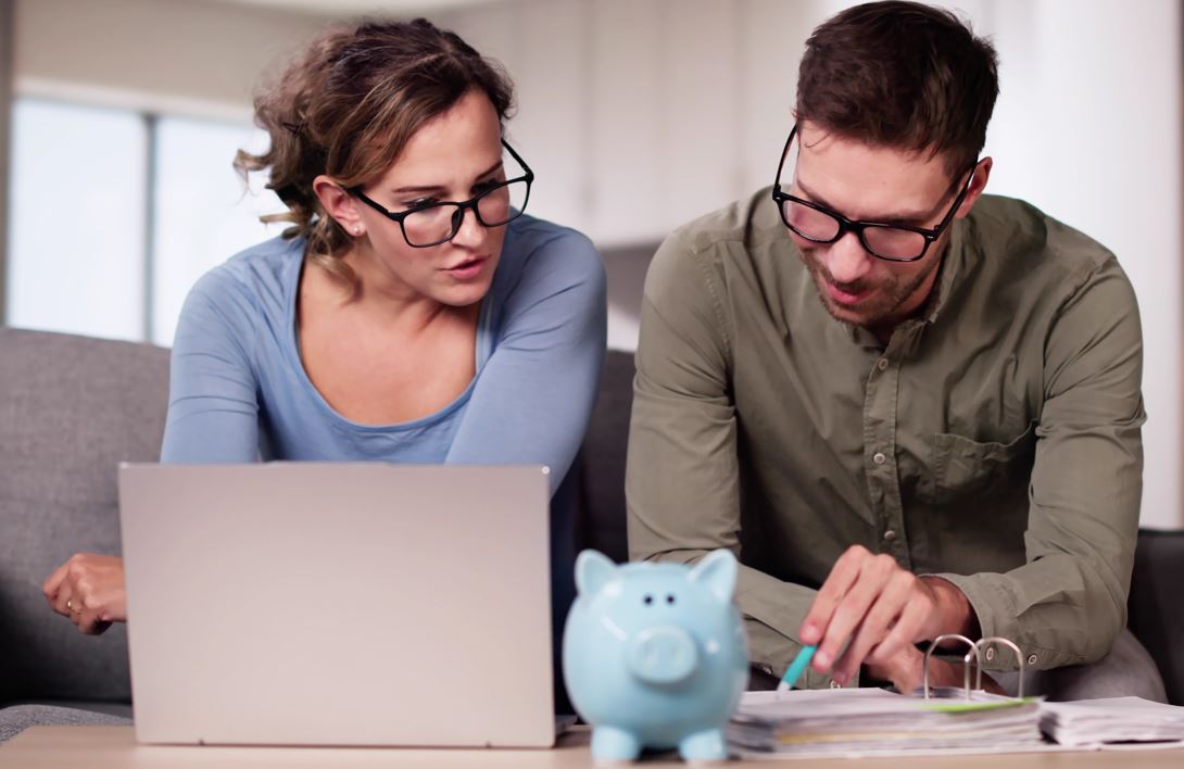 Ein Mann und eine Frau betrachten finanzielle Dokumente und einen Laptop.