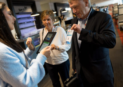 Ein Mann und zwei Frauen stehen in einem Geschäft und betrachten eine Technologie. Die Frau hält ein Tablet.