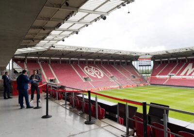 Ein Fußballstadion mit roten Sitzen und grünem Rasen. Die Allianz Arena in München.