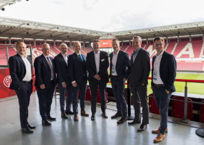 Männer in Anzügen stehen im Stadion, Geschäftsleute im Fußballstadion