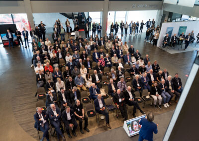 Ein Business-Meeting im großen Konferenzraum. Der Referent steht vor einem großen Publikum.