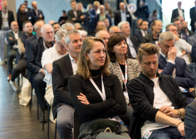 Ein Mann und eine Frau sitzen in einem Publikum. Die Dame sieht interessiert aus.