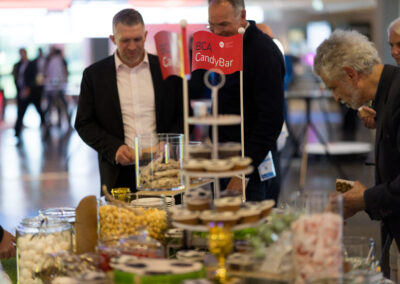 Ein Mann in einem schwarzen Mantel steht an einem Tisch mit Süßigkeiten und Snacks.