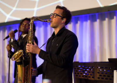 Ein Saxophonist spielt auf der Bühne, begleitet von einem Sänger.