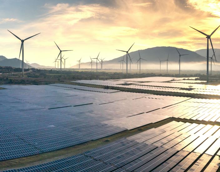 Eine Solarenergie-Anlage mit Photovoltaik-Modulen und Windkraftanlagen in einer bergigen Landschaft bei Sonnenuntergang. Die Anlage erzeugt saubere Energie.